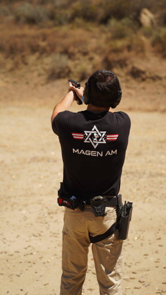 A person shooting in a Magen Am t-shirt.